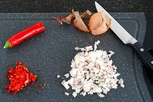 Zwiebel und Peperoni in Würfel schneiden