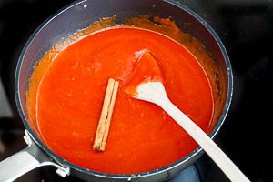 Passierte Tomaten und Zimtstange hinzugeben