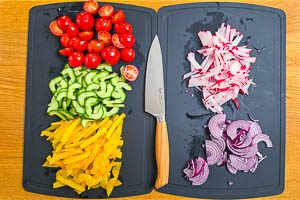 Tomaten, Gurke, Paprika, Zwiebel und Radieschen schneiden