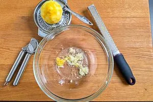 Zitronenzeste, Zitronensaft und Knoblauch in eine Sch&uuml;ssel geben