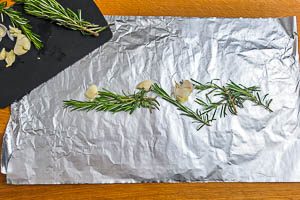 Rosmarin und Knoblauch auf Alufolie verteilen