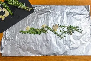 Rosmarin und Knoblauch auf Alufolie verteilen