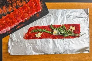 Eine Sch&auml;lrippe darauf legen, mit Knoblauch und Rosmarin belege