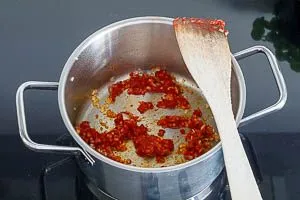 Zwiebel, Knoblauch und Tomatenmark in Oliven&ouml;l d&uuml;nsten.