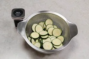 Zucchini in einem Sieb salzen