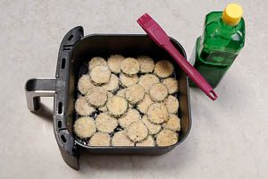 Airfryer mit &Ouml;l bespr&uuml;hen und Zucchinischeiben hineingeben