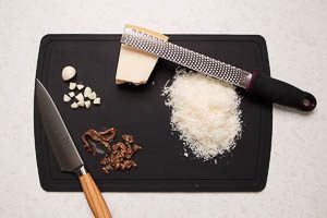 Knoblauchzehe schneiden, Sardellenfilets hacken und Parmesan reiben
