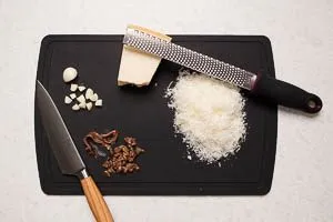 Knoblauchzehe schneiden, Sardellenfilets hacken und Parmesan reiben