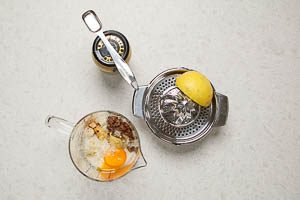 Parmesan, Sardellen, Knoblauch, Dijon Senf, Zitronensaft, Worcestersauce und Eigelb in den Rührbecher