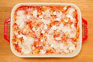 Parmesan und Mozzarella auf die Gnocchi geben