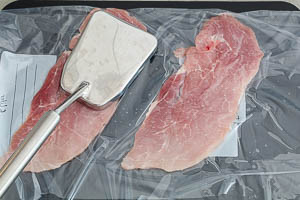 Schnitzel mit Pflanzenöl in einen Gefrierbeutel geben und mit einem Plattiereisen klopfen