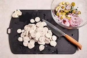 Gem&uuml;se in die Sch&uuml;ssel geben und Wei&szlig;w&uuml;rste h&auml;uten