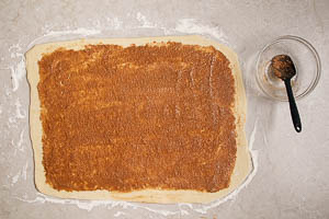 F&uuml;llung aus Zimt, Zucker und Butter auf dem ausgerollten Teig verstreichen