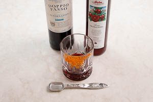 Granatapfelsirup und Rotwein ins Glas geben.
