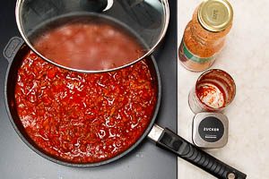 Passierte und st&uuml;ckige Tomaten in die Pfanne geben
