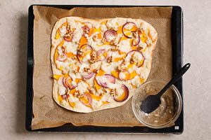 K&uuml;rbis-Flammkuchen nach dem Backen mit Honig betr&auml;ufeln und mit N&uuml;ssen belegen