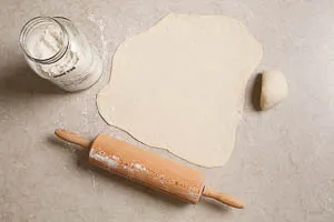 Flammkuchenteig-Fladen glatt ausrollen