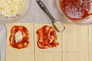 Teig-Quadrate mit Tomatenso&szlig;e bestreichen und mit K&auml;se bestreuen
