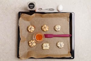 Rohe Pumpkin-Pizzabr&ouml;tchen mit gew&uuml;rztem Ei bepinseln