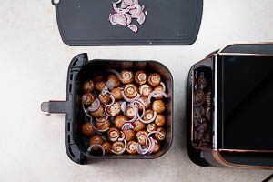 Marinierte Champignons und Zwiebeln auf dem Gitter im Airfryer verteilen