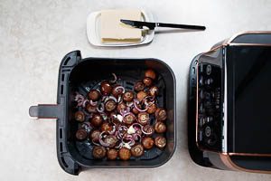 Butterflocken zu den Zwiebeln und Champignons in den Airfryer geben