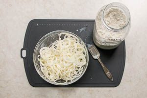 Zwiebeln in Halbringe schneiden und mit Mehl vermengen