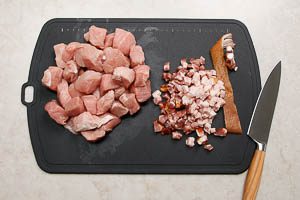 Schweinefleisch und Speck in W&uuml;rfel schneiden