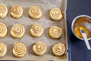 Zimtschnecken auf dem Backblech mit Eigelb bestreichen